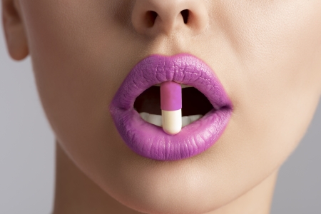 sensual female mouth in close-up portrait with coloured pill between lips  の写真素材