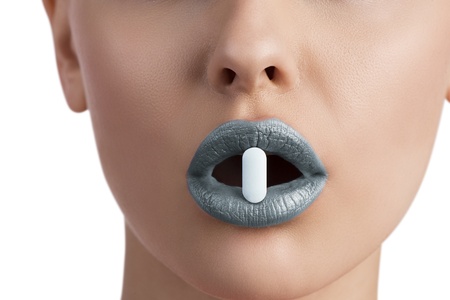 close-up of sensual female mouth with blue lipstick taking one pill between lips の写真素材