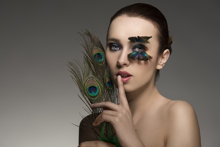 beauty portrait of sensual brunette girl with naked shoulders and elegant make-up and accessory inspired by peacock feather  の写真素材