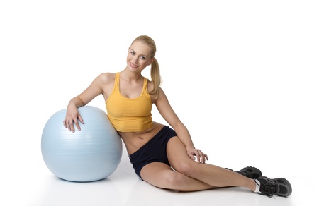 young pretty woman with fitness dress sitting on white and looking in cameraの写真素材