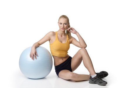 fitness girl in gym dress sitting on white with a ball near her . natural skinの写真素材