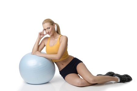 blond beautiful woman in fitness dress sitting near a big ball smiling . NATURAL SKINの写真素材