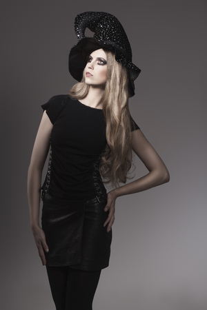 portrait of fashion Halloween woman with gothic style, leather skirt, witch hat and creative make-up の写真素材