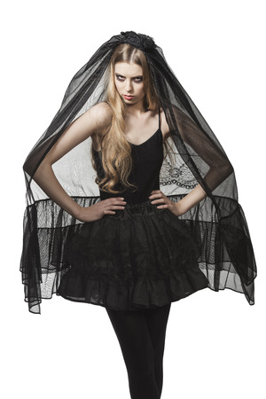 portrait of blonde girl with Halloween costume, funeral style and creative make-up wearing long dark veil and bizarre skirtの写真素材