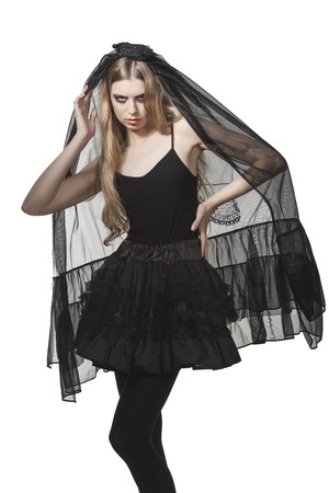 pretty girl with long blonde hair, creative make-up and grotesque clothes for Halloween party. Wearing long dark veil and gothic skirt の写真素材