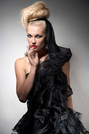 attractive woman with blonde creative hair-style and Halloween look. Wearing dark bizarre dress, silver jewellery and cute make-up  の写真素材