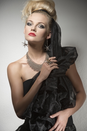 Halloween portrait of cute blonde girl with dark elegant dress and creative make-up and hair-style. Wearing silver accessories and looking in camera   の写真素材