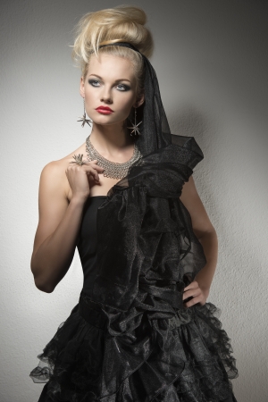 portrait of sensual blonde girl with Halloween costume, creative make-up and hair-style. Wearing bizarre dark dress and silver accessory. の写真素材