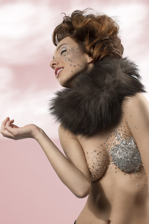 glamour portrait of sexy brunette woman with creative hair-style, fur collar and glittering decorations on her make-up and naked body の写真素材