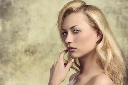 sensual blonde woman with long natural hair-style, colorful make-up and bared shoulders posing in close-up portrait and looking in camera with sensual expression の写真素材