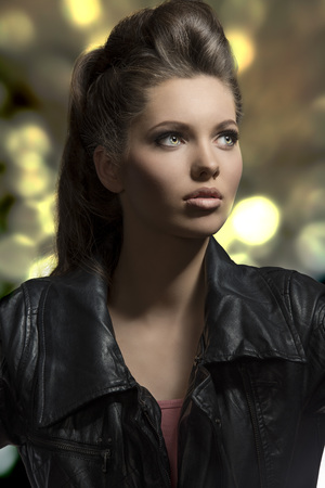 close-up fashion portrait of sensual young girl with brown rock hair-style wearing modern  clothes, black leather jacketの写真素材