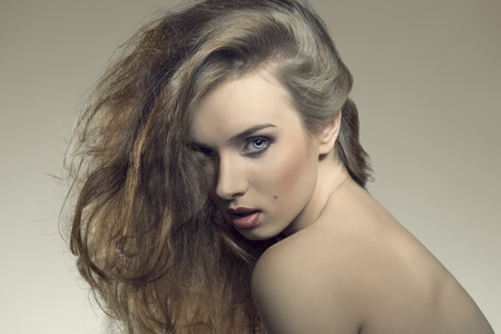 close-up portrait of attractive young female posing with provocative expression with naked shoulders and wild bushy hair の写真素材