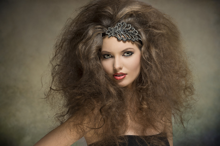 young caucasian woman posing in fashion portrait with voluminous curly hair-style, glitter accessory in the hair and cute make-up の写真素材