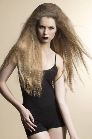portrait of sexy woman with dark style, long blonde creative flying hair-style and strong make-up posing with black underwearの写真素材