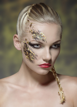 pretty young girl with blonde bride hair-style and naked shoulders posing with creative strong make-up on her perfect visage の写真素材