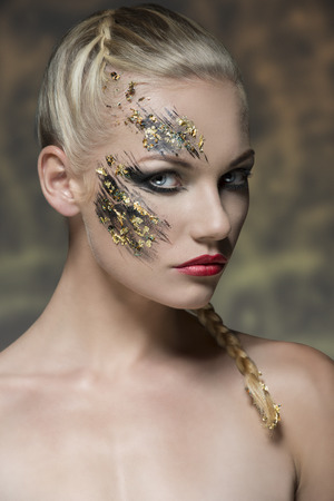 sexy blonde girl posing in beauty portrait with bride hair-style, naked shoulders and strange strong creative make-up の写真素材