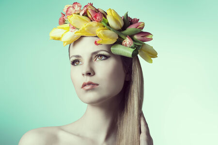 close-up portrait of beauty girl with perfect skin and romantic expression, posing with spring floral garland on her head and colorful make-up の写真素材