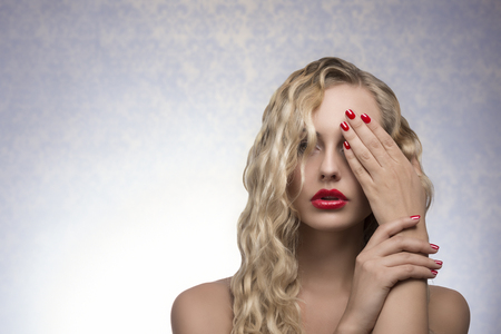 cute blonde female with long wavy hair, red lips and nail polishの写真素材