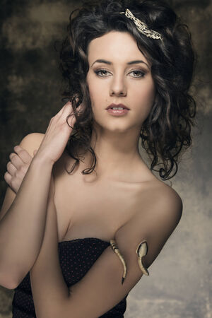 portrait of amazing brunette woman with sexy low-necked dress, creative jewels and cute curly hair-style. Fashion elegant portrait  の写真素材