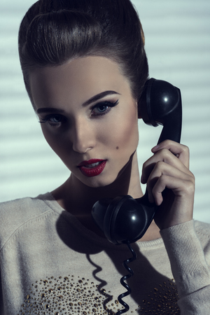 close-up shoot of charming elegant lady talking on vintage phone with receiver の写真素材