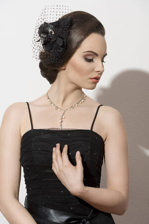 fashion shoot of lovely brunette lady posing with dark evening dress and elegant accessories, cute make-up and hair-style の写真素材