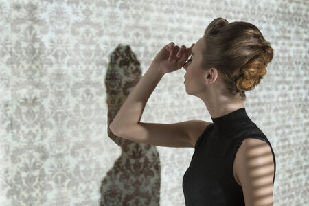 fashion shoot in indoor half-light atmosphere of sensual girl with elegant style in dramatic pose の写真素材