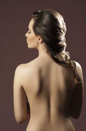 sensual brunette female showing her base back and creative elegant hair-style の写真素材