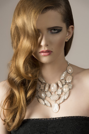 close-up of very pretty female with elegant wavy hair-style, sexy black dress and stylish necklace. の写真素材