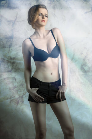charming girl with fashion hair-style wearing sexy black bra and shorts, in sensual pose. color effect の写真素材