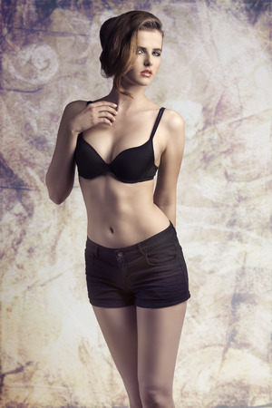 sexy young girl posing with cute make-up, elegant hair-style, wearing black shorts, in sensual pose の写真素材