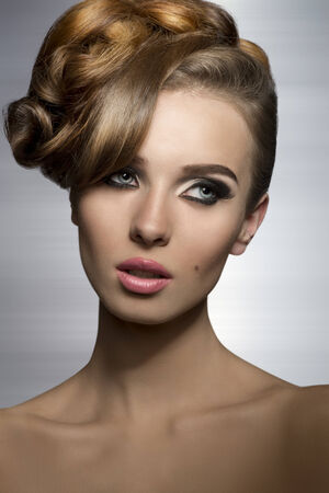 lovely girl with stylish make-up and creative elegant hair-style posing in beauty shoot の写真素材