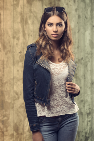 sensual young female with natural wavy hair-style posing with denim fashion clothes and lace white shirt. Trendy sunglasses on the head の写真素材