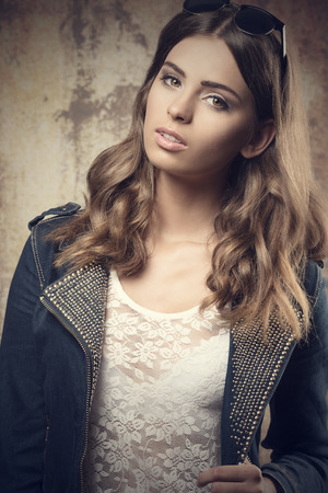 very pretty young lady in natural pose in fashion shoot wearing denim jacket, lace skirt and trendy sunglasses の写真素材