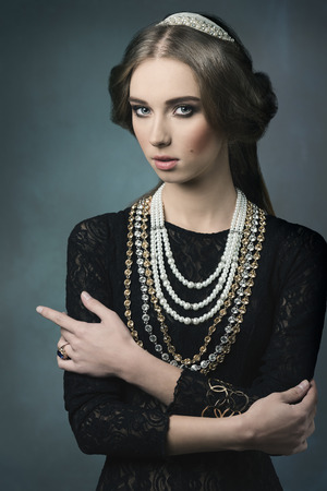 vintage portrait of beautiful brunette woman posing like a antique dame with precious crown and necklaces, retro hair-style の写真素材