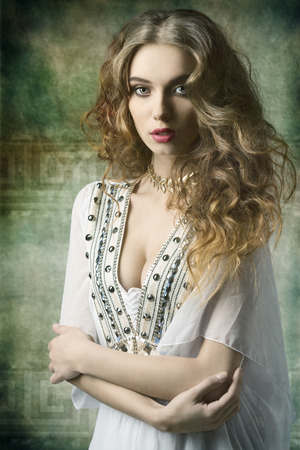 lovely dame with antique style and golden jewellery posing with curly long hair and looking in cameraの写真素材
