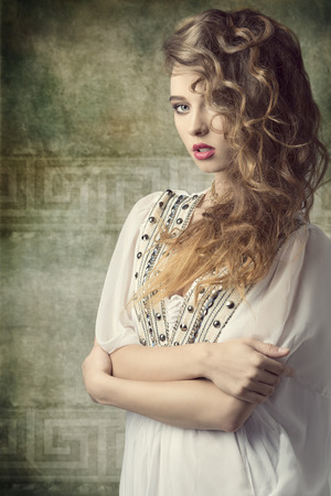 sexy curly woman with stylish make-up posing like a antique dame with vintage dress and jewelleryの写真素材