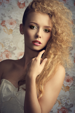 curly pretty girl with blonde stylish hair-style and natural make-up posing in close-up fashion portrait and wearing white lovely dressの写真素材