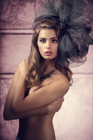 glamour shoot of very pretty woman with naked breast  and bizarre, big tulle accessory in the head. Fashion creative styleの写真素材