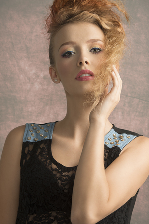 Close up portrait od young woman, she has got blonde, wavy hair and colorful makeup. She is wearing black top.の写真素材