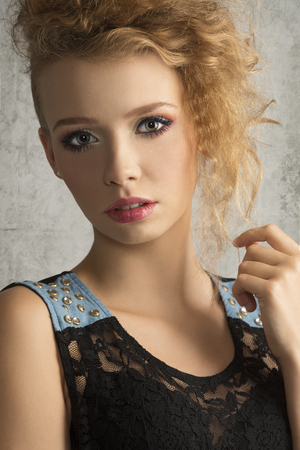 Fresh, young blonde girl with crazy hairstyle and colorful makeup is looking at camera.の写真素材