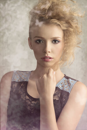 Young, pretty girl with blonde wild hair is wearing transparent black blouse with denim parts. She has got colorful make up .の写真素材
