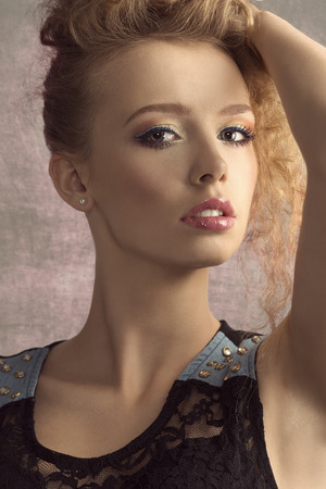 Beautiful, young girl with blonde, wavy hair and nice, colorful, fresh make up. She is looking at camera. She wears black top.の写真素材