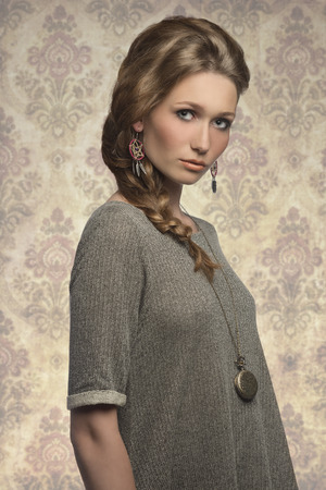 fashion portrait of cute blonde girl with long braid hair-style, gray dress and stylish necklaceの写真素材
