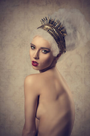 nude glamour woman with cute make-up posing with artistic crazy hair-style and golden accessoriesの写真素材
