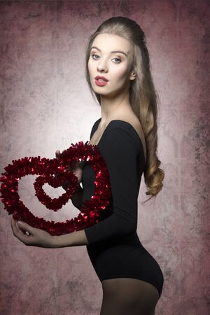 Young, beautiful, romantic valentines girl with curly hairstyle and with valentine heart.の写真素材