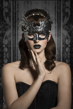 Mysterious, carnival, elegant, gorgeous female in silver mask with black lips and old fashioned hairstyle.の写真素材