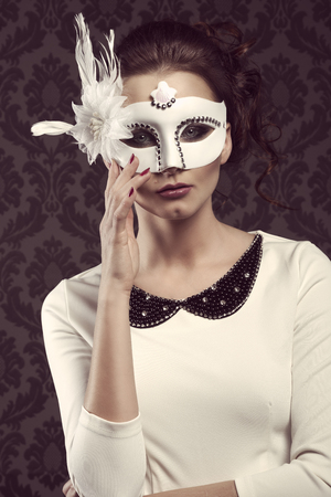 vintage portrait of nice woman , in elegant white dress and mask looking in camera . ready for partyの写真素材