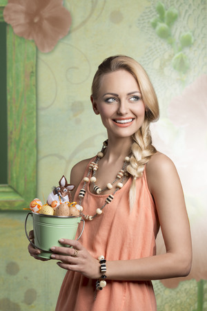 easter portrait of beautiful blonde woman with spring style and bucket with decorated easter eggs, she smilingの写真素材