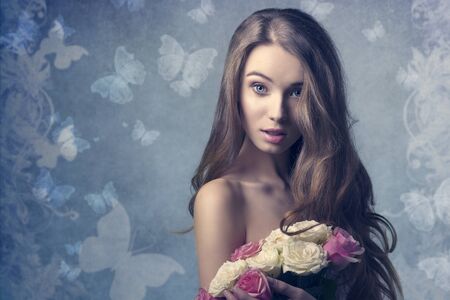 sexy woman with long natural hair posing with surprised expression, looking in camera and taking bouquet of roses in the handsの写真素材
