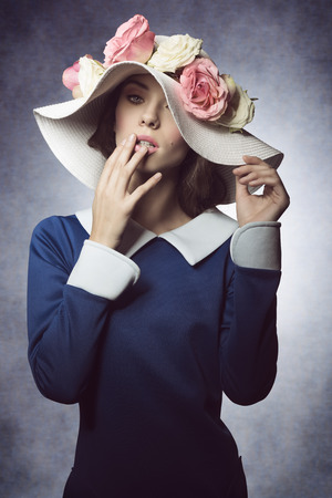 old fashioned young woman with blue dress and a white hat with some flower as ornamentの写真素材